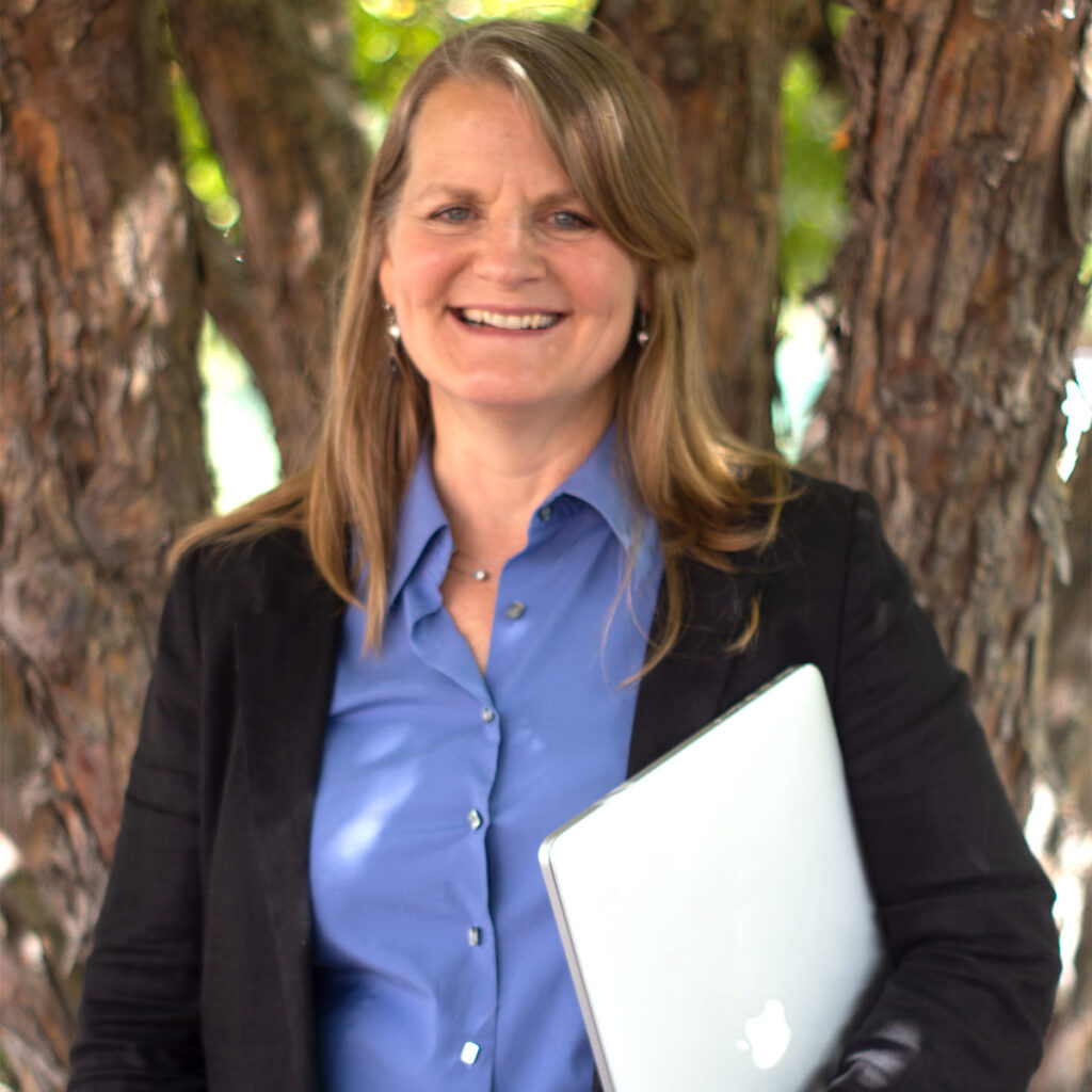 Abigail Moore, DO, smiling, photographed outdoors in front of a large pine tree.