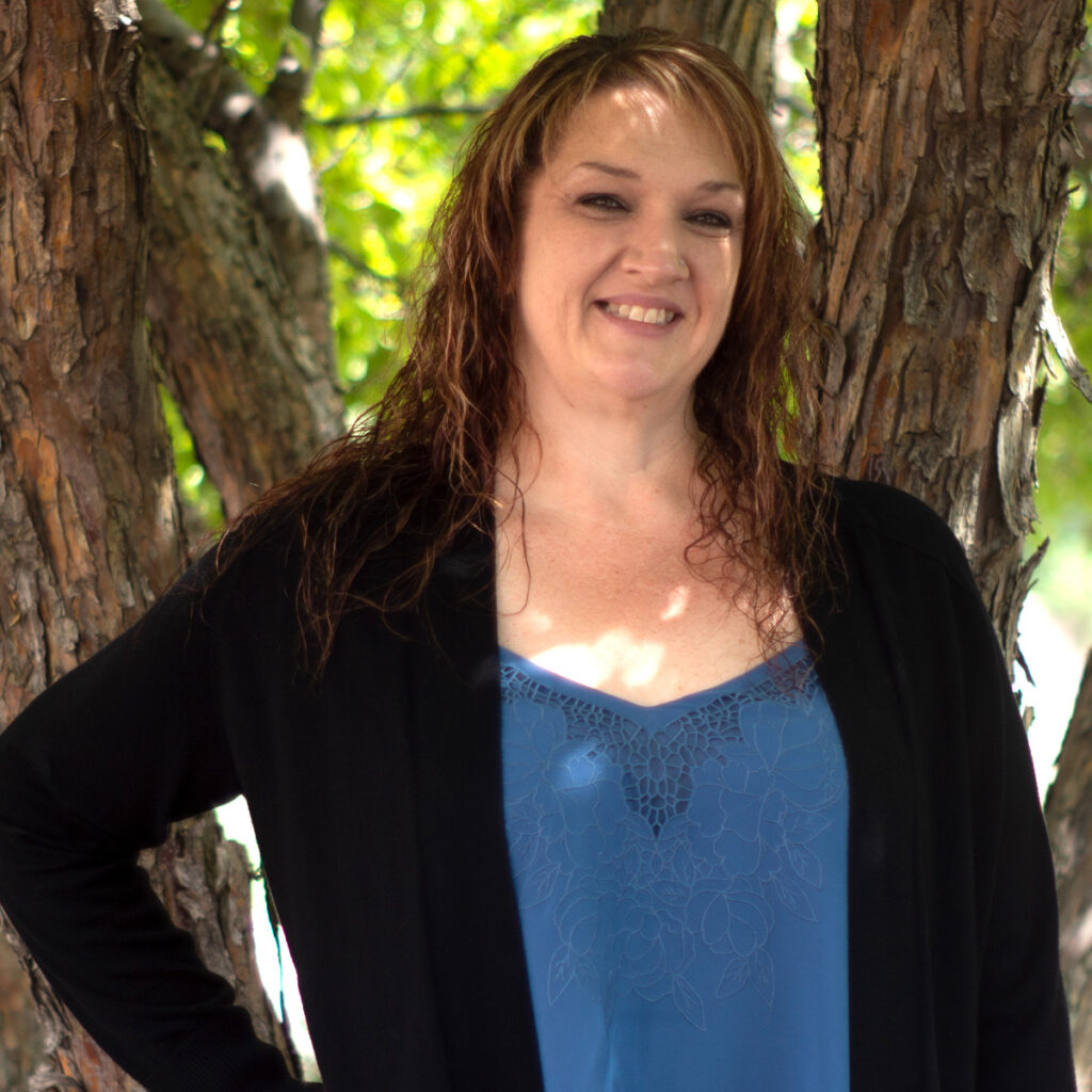 Sherry Mason, smiling, photographed outdoors in front of a tree.